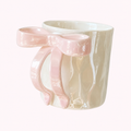 Taza de cerámica nacarada con asa en forma de lazo rosa y textura ondulada